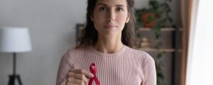 Close da mão de uma mulher segurando um laço vermelho, símbolo da luta contra a AIDS