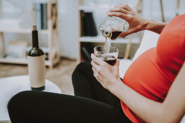 Mulher grávida colocando bebida no copo