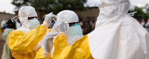 Foto de profissionais de saúde vestindo EPIs brancas e amarelas durante surto de ebola na Uganda; o vírus é da mesma família que o Marburg