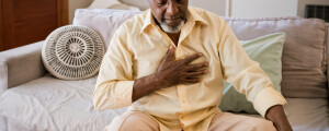 Homem sentado no sofá com a mão no peito sentindo dor