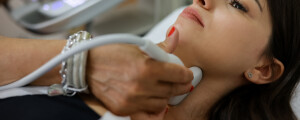 Imagem aproximada de uma mulher tendo o pescoço examinado por um médico usando um ultrassom