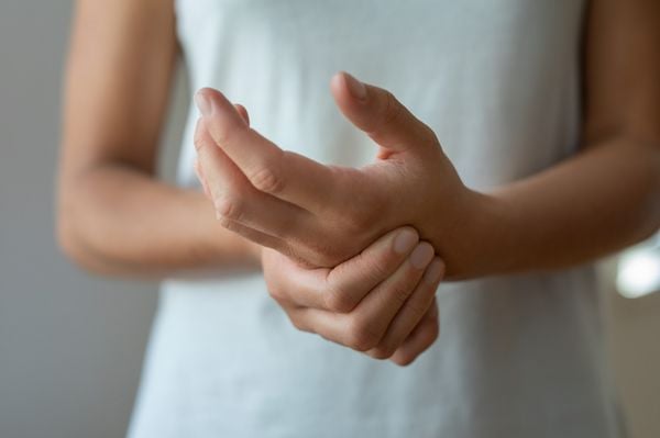 Imagem aproximada de mulher segurando o pulso ao sentir dor; a dor nas articulações é um dos sintomas de lúpus