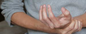 Imagem aproximada de homem segurando o pulso ao sentir dor; a dor nas articulações é um dos sintomas de lúpus