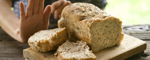 Close de uma mão em sinal de negação em frente a uma tabua com pães