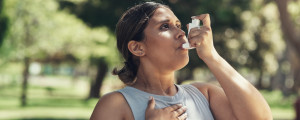 Mulher usando sua bombinha de asma durante treino ao ar livre