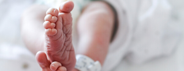 pés enrugados e pernas entrelaçados de um recém-nascido deitado em uma cama que parece ser de hospital
