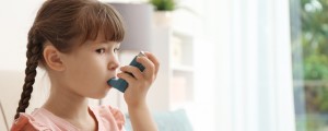 Criança pequena com uma bombinha de asma na boca