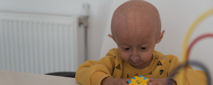 Criança branca com progeria brincando com jogo colorido de encaixar