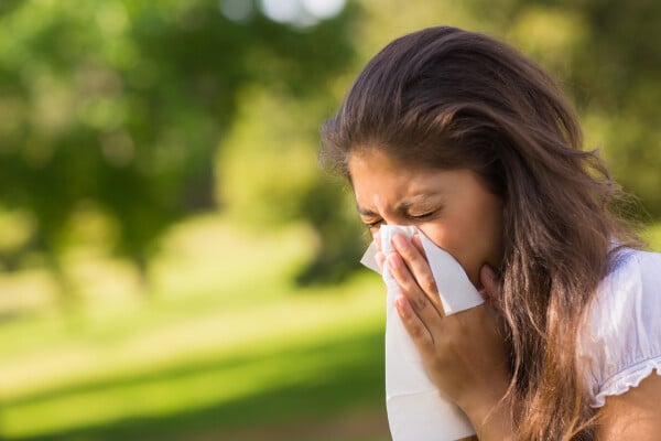 Mulher assoando o nariz devido a alergia respiratória