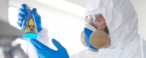 Cientista equipado com máscara de laboratório segurando um líquido de risco biológico