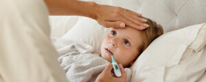 Mãe medindo a temperatura da filha com febre