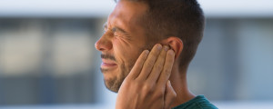 Homem segurando o ouvido sentindo dor