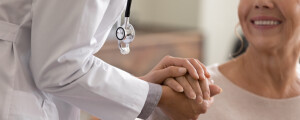 Profissional de saúde segura a mão de paciente.