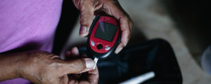 Homem testando o nível de glicose no sangue, parte do tratamento do diabetes