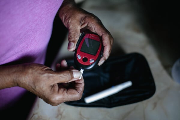 Homem testando o nível de glicose no sangue, parte do tratamento do diabetes