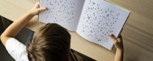 Menino segura livro com diversas letras embaralhadas, representando a dislexia