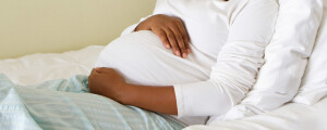 Mulher grávida repousando com as mãos sobre a barriga