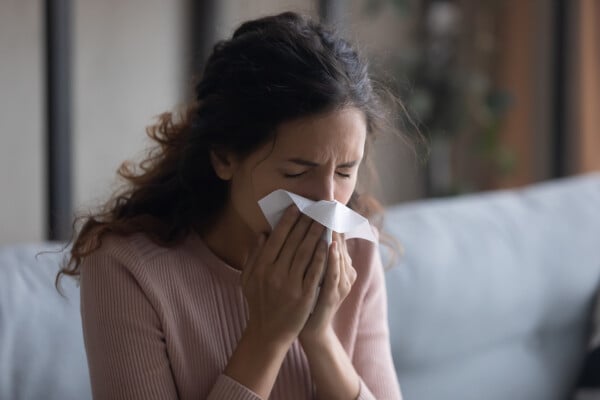 Mulher assoando o nariz com rinite alérgica