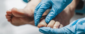 Close das mãos de um médico examinando o pé de um paciente