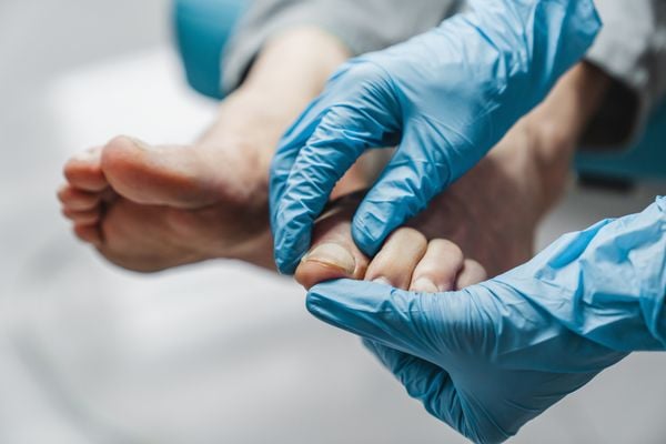 Close das mãos de um médico examinando o pé de um paciente
