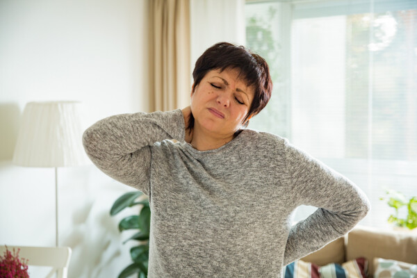 Mulher madura com dores no pescoço e na lombar, sintomas típicos da fibromialgia