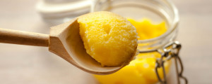 Pote de manteiga ghee com colher de manteiga ghee acima do pote