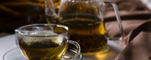 bule com chá de insulina vegetal em uma mesa de madeira ao lado de uma xícara de chá