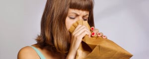 Mulher usando um saco de papel tentando respirar