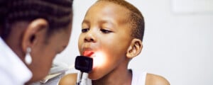 médica avaliando a garganta de um paciente infantil