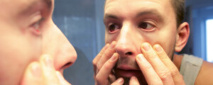 Homem analisando os olhos no espelho