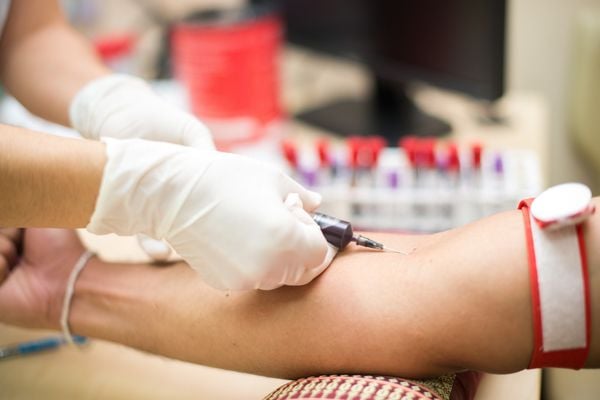 Médico removendo amostra de sangue do braço de um paciente