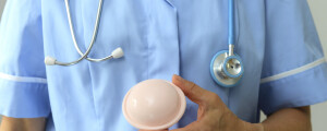 Contraceptivo diafragma sendo segurado na mão de um médico