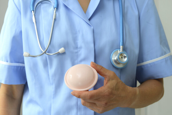 Contraceptivo diafragma sendo segurado na mão de um médico