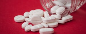Imagem de alguns comprimidos espalhados em uma superfície vermelha