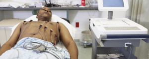 Homem deitado em uma maca fazendo exame eletrocardiograma