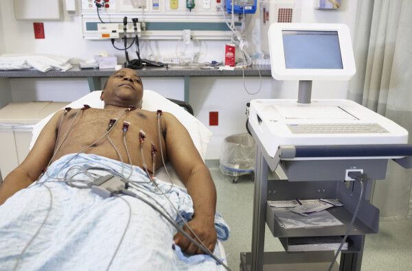 Homem deitado em uma maca fazendo exame eletrocardiograma