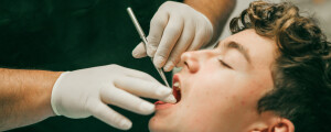 Dentista observando os dentes de um paciente adolescente
