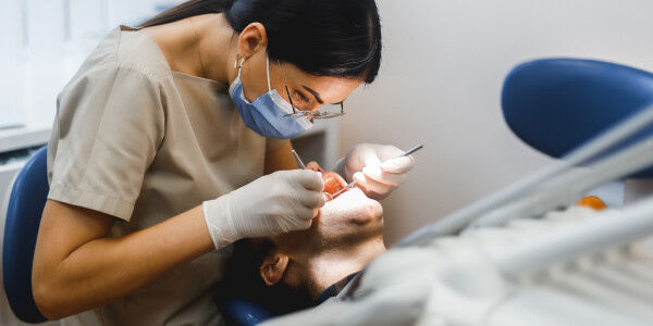 Dentista fazendo um procedimento odontológico em um paciente deitado em uma maca