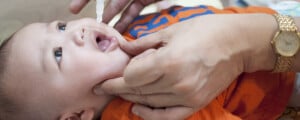 bebê deitado recebendo a vacina rotavírus pentavalente, em forma de gota