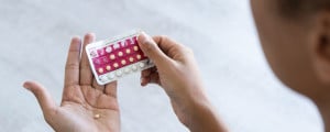 Imagem de mulher colocando pílula anticoncepcional na mão